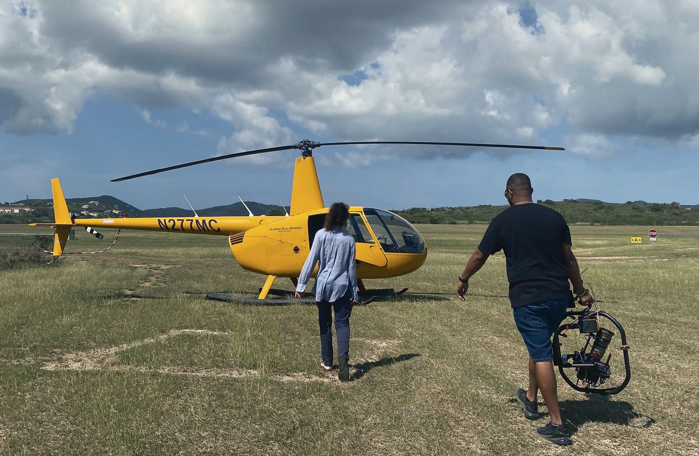 Dwight Winston walking to a helicopter with a gimbal camera rig for an aerial shoot